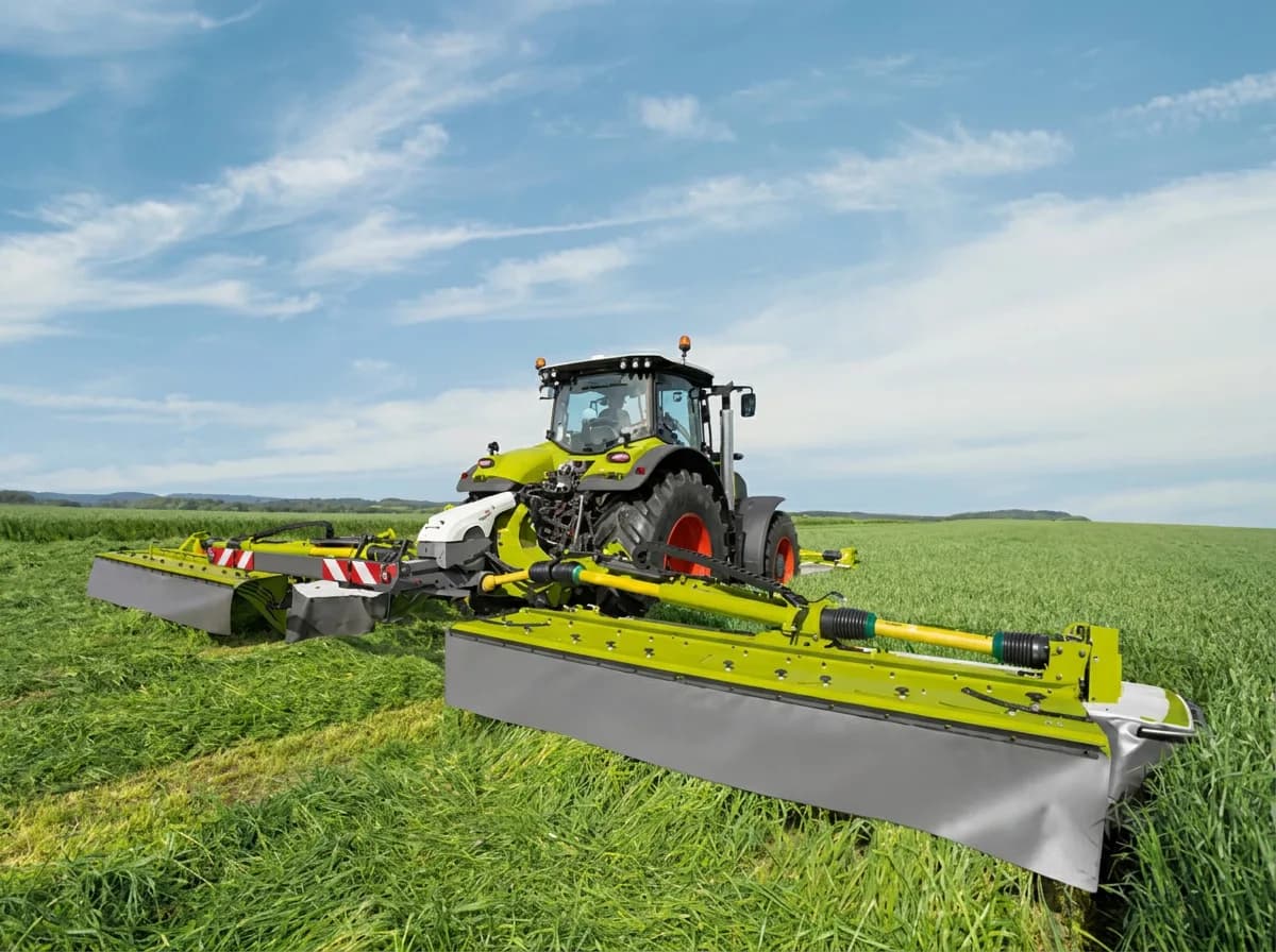 Claas Arion tractor mowing grass with a Claas Disco rear butterfly mower combination, both units down and cutting