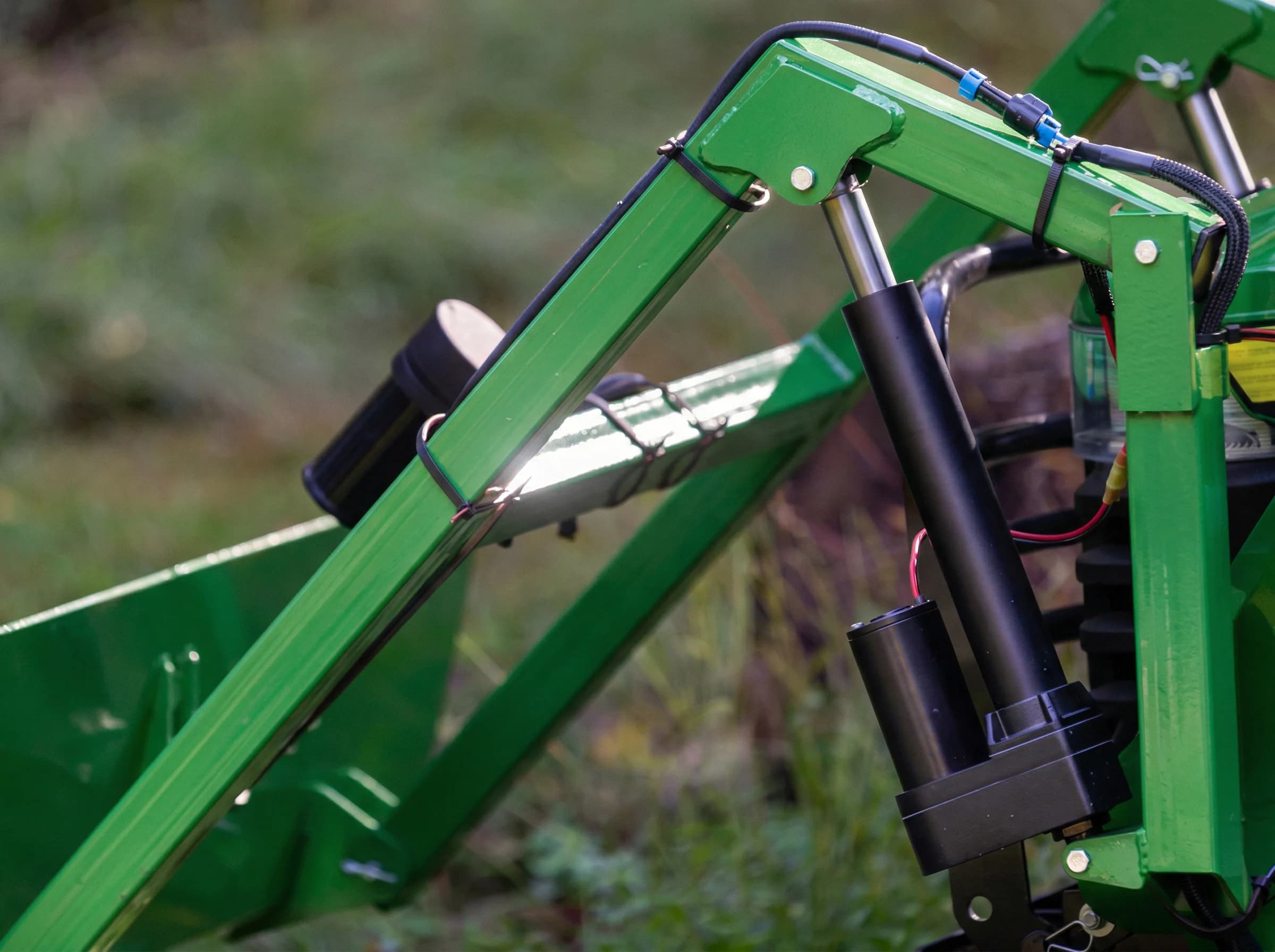 12V electric linear actuator mounted on a green agricultural loader arm