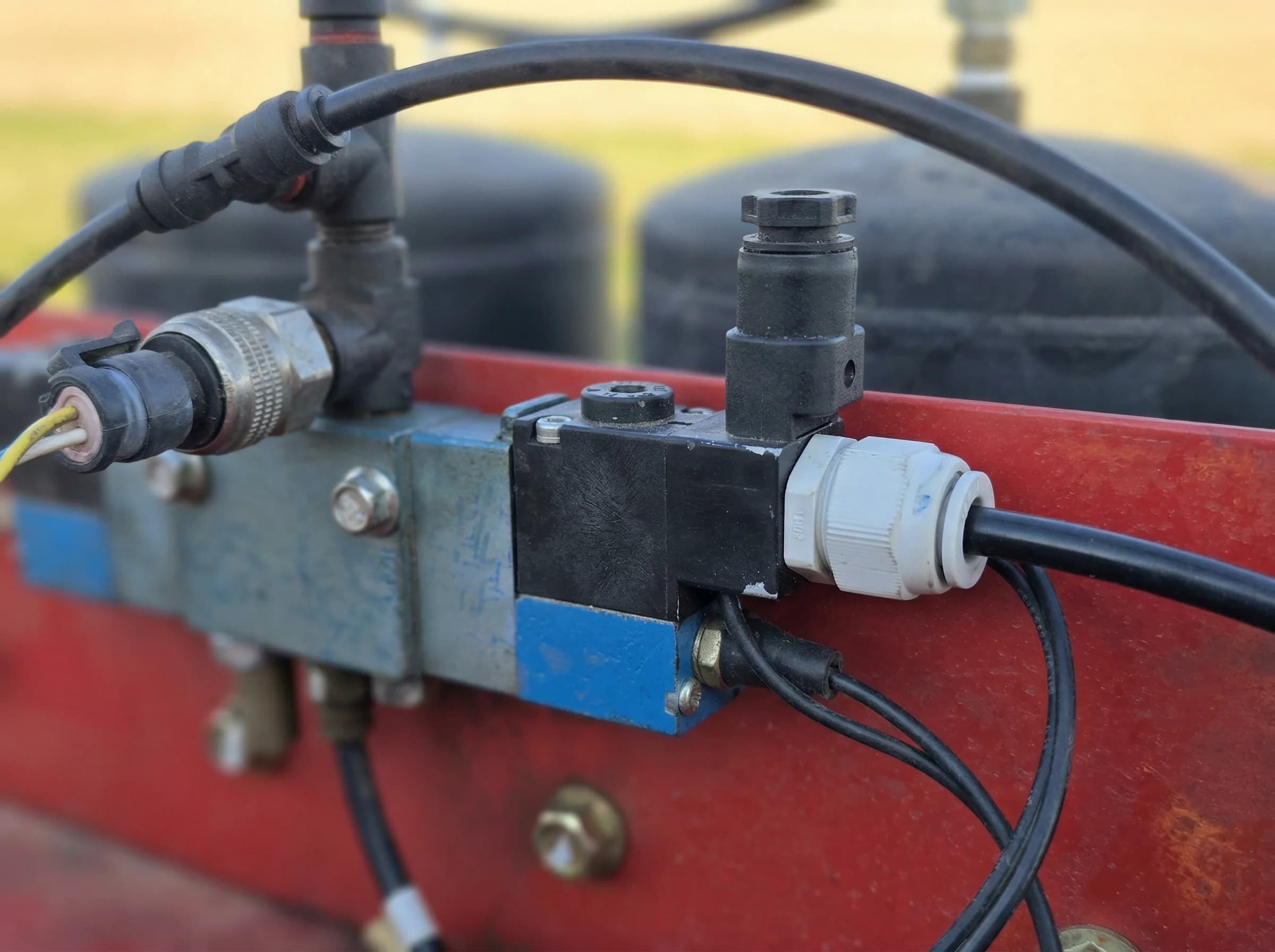 Pneumatic solenoid valve block with push-fit air fittings on an agricultural implement frame