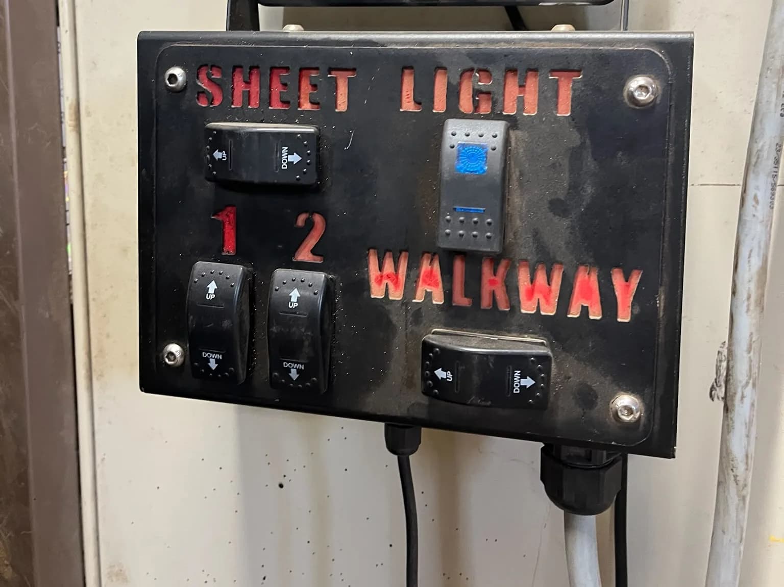 An old switch box mounted in a tractor cab, rocker switches under hand-painted labels for sheet light and walkway