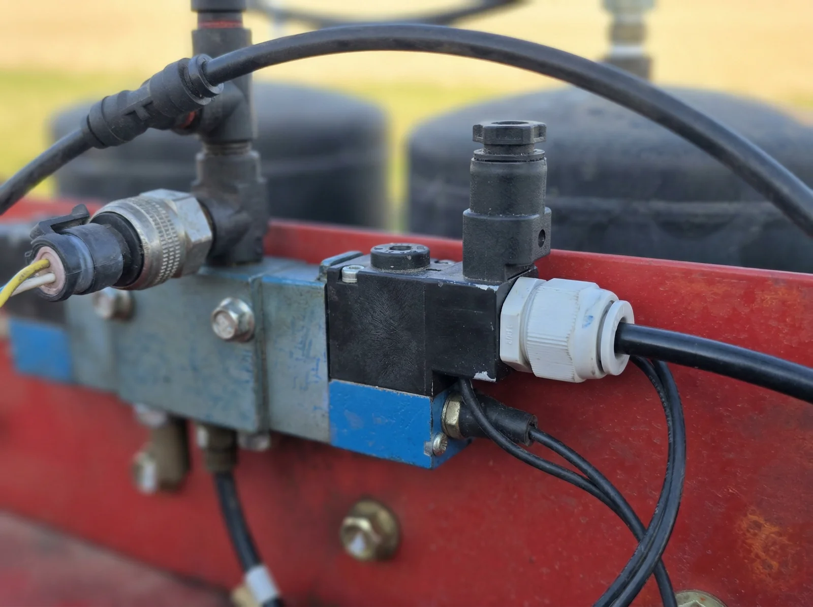 Pneumatic solenoid valve manifold mounted on the red frame of a sectioned implement, connected with airlines